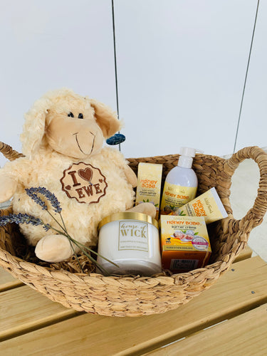 A gift basket with a fluffy toy, candle, cream, spray and shampoo